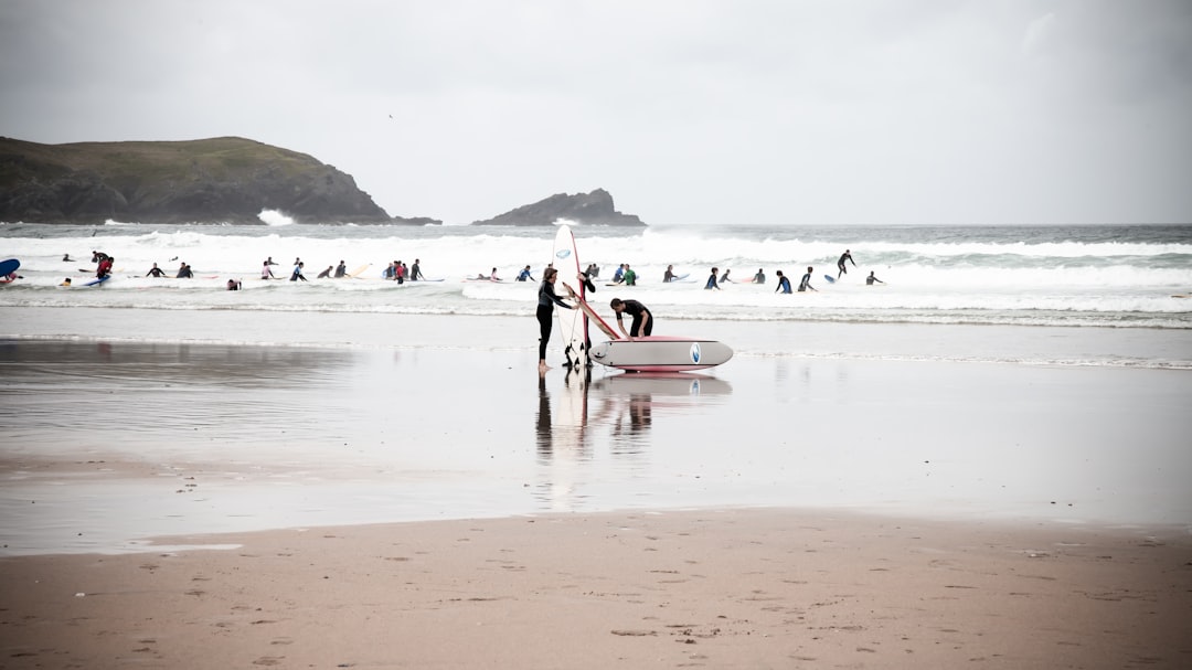 man in white shirt and black pants holding white surfboard on beach during daytime