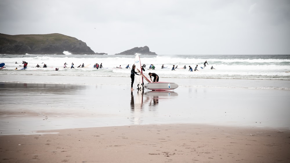 man in white shirt and black pants holding white surfboard on beach during daytime