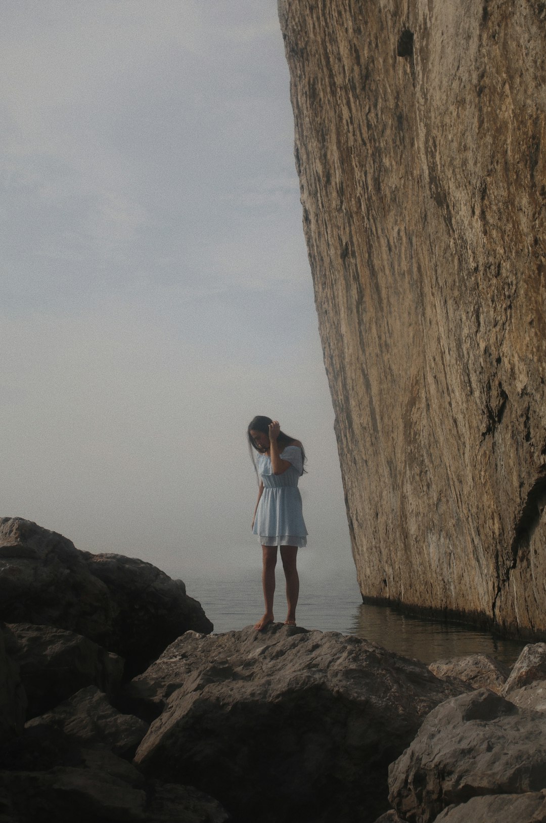 woman in white t-shirt standing on brown rock formation during daytime