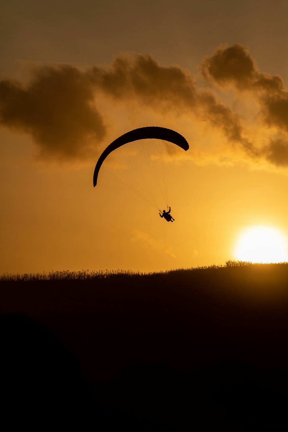 silhouette of person riding parachute during sunset