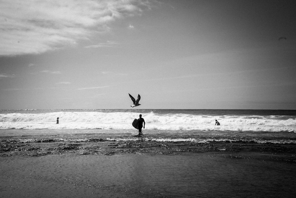 grayscale photo of man walking on beach