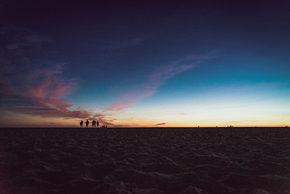 Gente caminando sobre la arena durante la puesta del sol