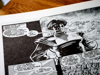 A black-and-white comic book page featuring a character wearing a futuristic or space-themed outfit. Speech bubbles contain dialogue about heavy gravity zones, adding a sci-fi narrative context. The artwork shows dynamic shading and expressive character design, capturing a sense of action and storytelling.