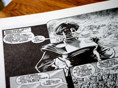 A black-and-white comic book page featuring a character wearing a futuristic or space-themed outfit. Speech bubbles contain dialogue about heavy gravity zones, adding a sci-fi narrative context. The artwork shows dynamic shading and expressive character design, capturing a sense of action and storytelling.