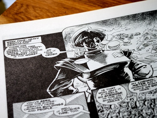 A black-and-white comic book page featuring a character wearing a futuristic or space-themed outfit. Speech bubbles contain dialogue about heavy gravity zones, adding a sci-fi narrative context. The artwork shows dynamic shading and expressive character design, capturing a sense of action and storytelling.