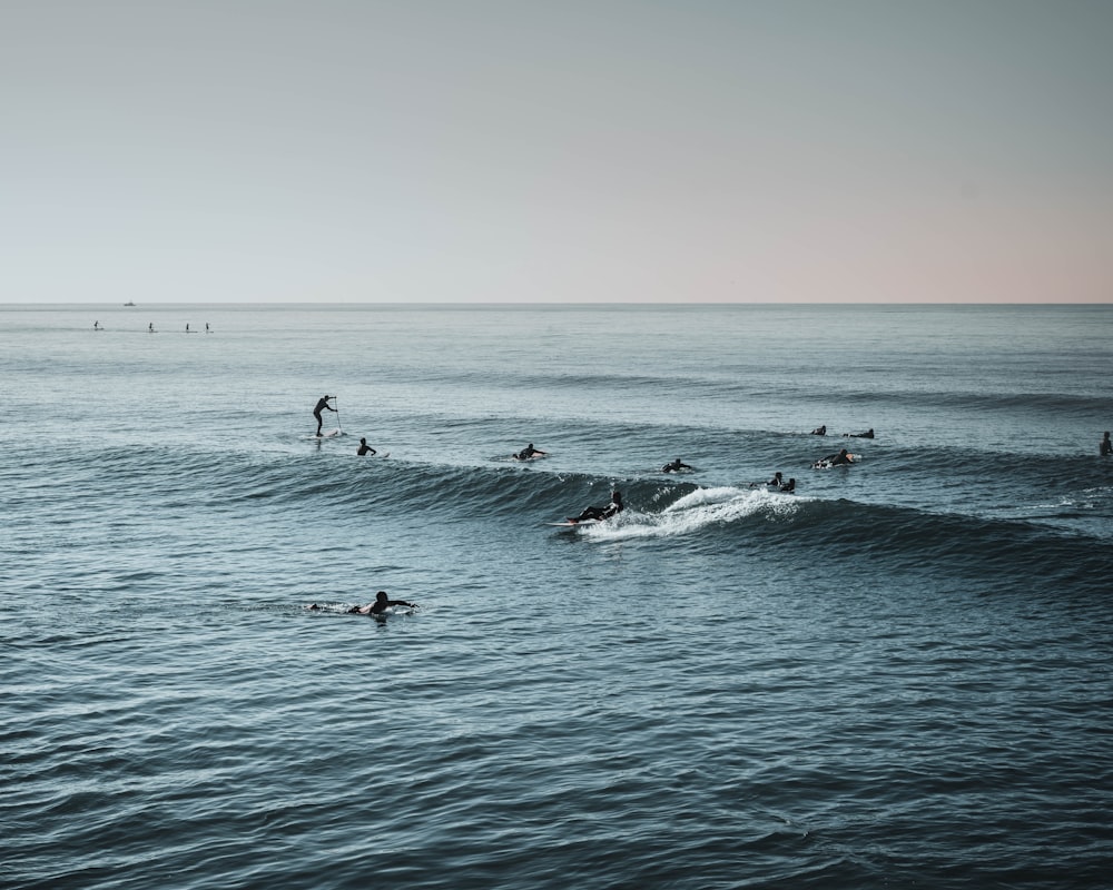 a group of people riding waves on top of surfboards