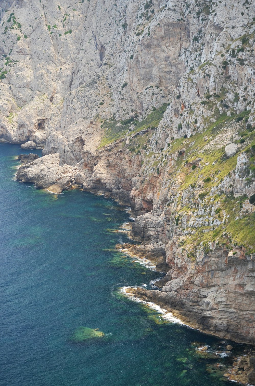 green and gray mountain beside blue sea during daytime