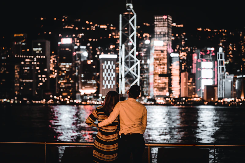 homme en chemise jaune et pantalon rayé assis sur un quai la nuit