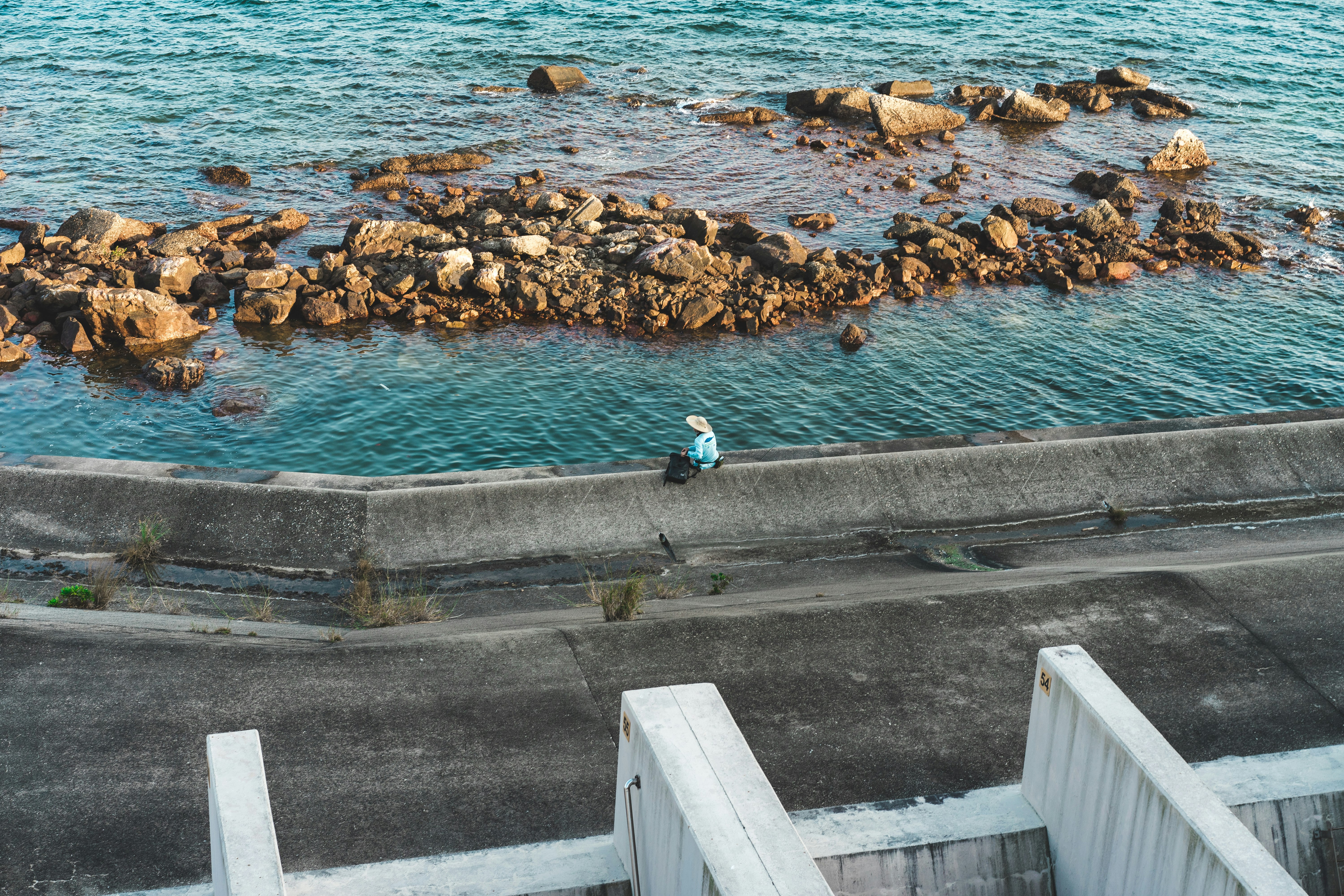 person in blue long sleeve shirt and blue denim jeans standing on gray concrete dock during