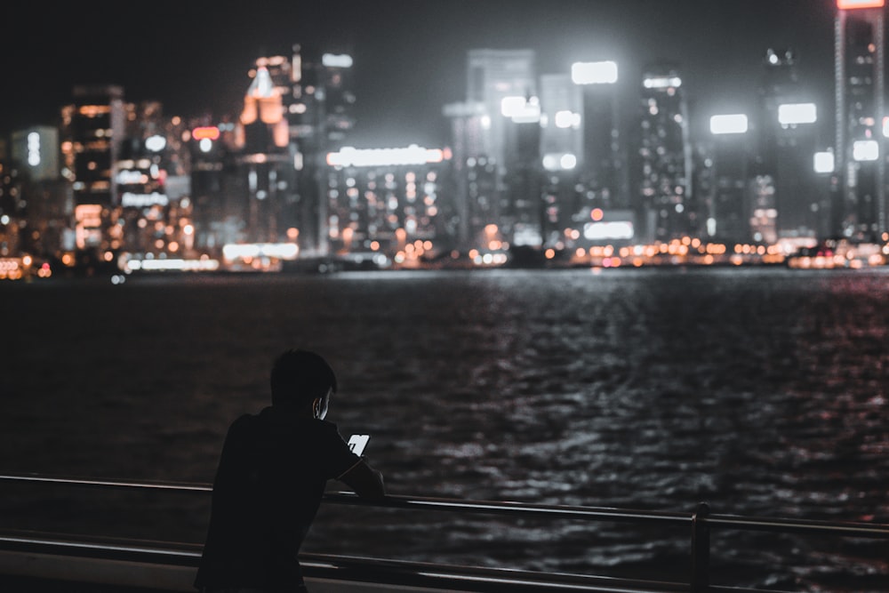 man in black hoodie standing on bridge during night time
