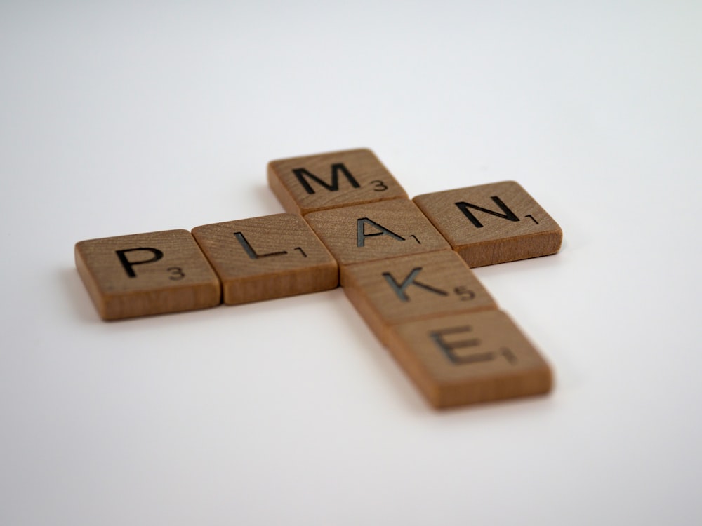 a scrabbled wooden cross with the word plan spelled on it