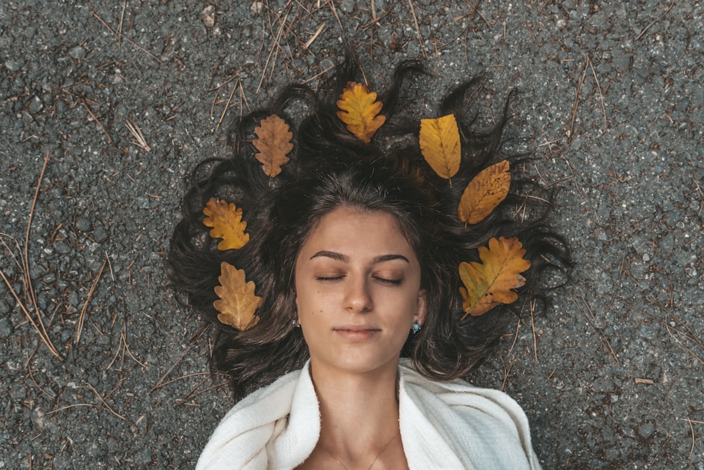 woman in white shirt lying on dried leaves