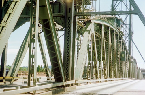 Close-up of a steel bridge framework spanning a wide river, emphasizing structural detail.