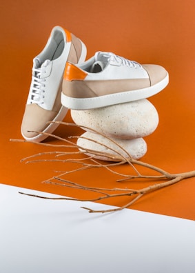 Flat lay of colorful sport shoes and accessories on an orange background with black graffiti accents.