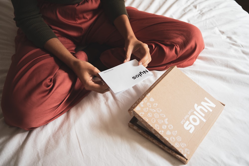 Person mit weißem Buch auf dem Bett