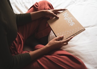 person in red long sleeve shirt holding brown book