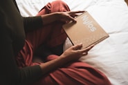person in red long sleeve shirt holding brown book