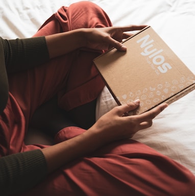 person in red long sleeve shirt holding brown book