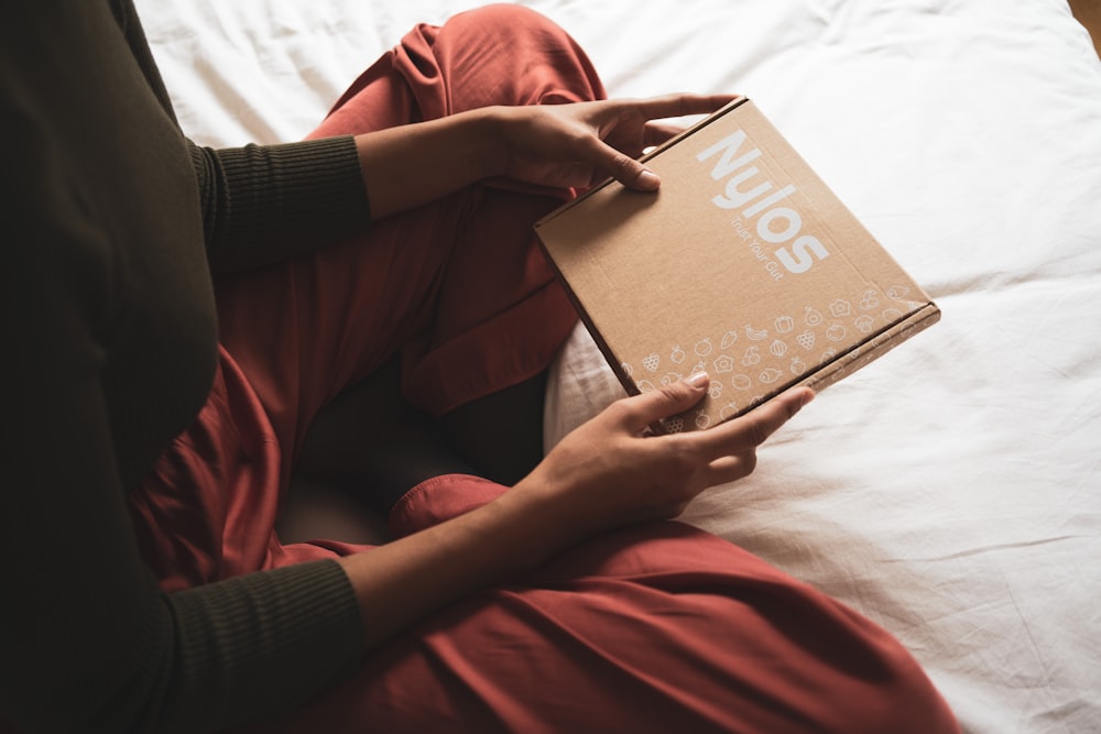 person in red long sleeve shirt holding brown book