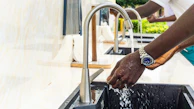 A maniwasher station with clean towels, soaps, and a client enjoying the hand washing service.