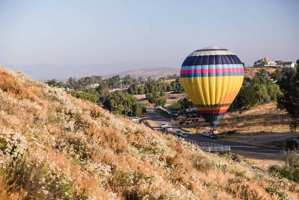 a colorful hot air balloon flying over a hill