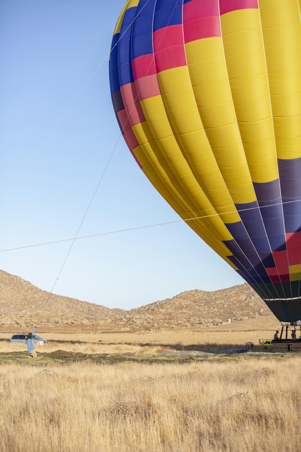 a hot air balloon flying over a dry grass field