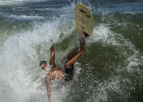 2 person surfing on sea waves during daytime