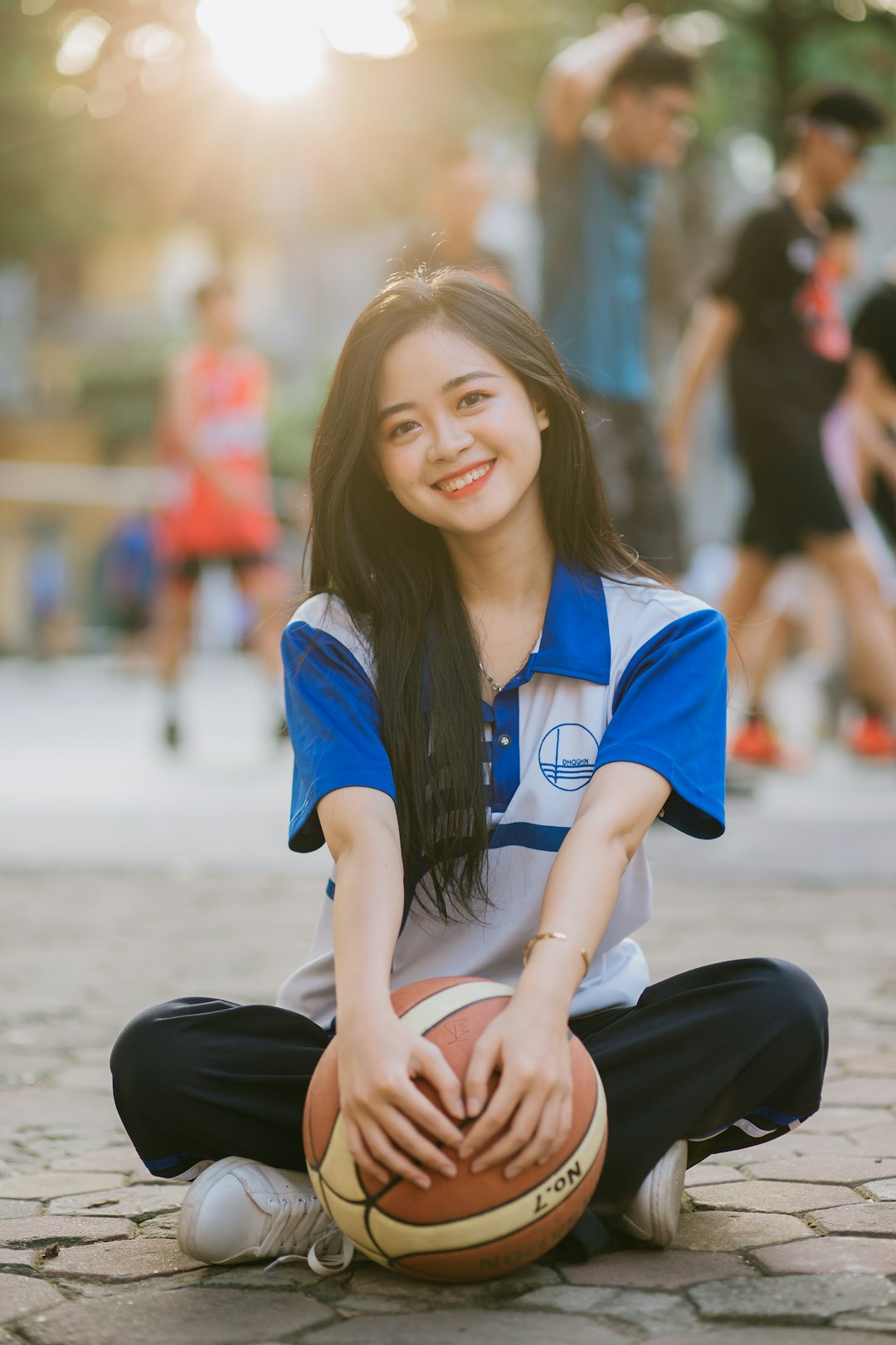 woman in blue and white shirt and black pants sitting on the ground