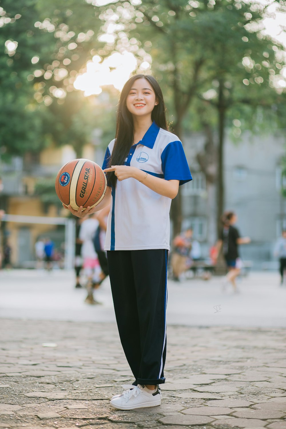 青と白の制服を着た女性がバスケットボールを手に