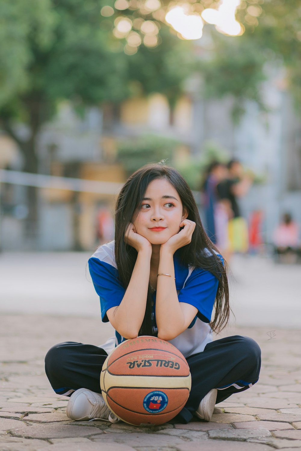 woman in blue long sleeve shirt and black pants sitting on the road