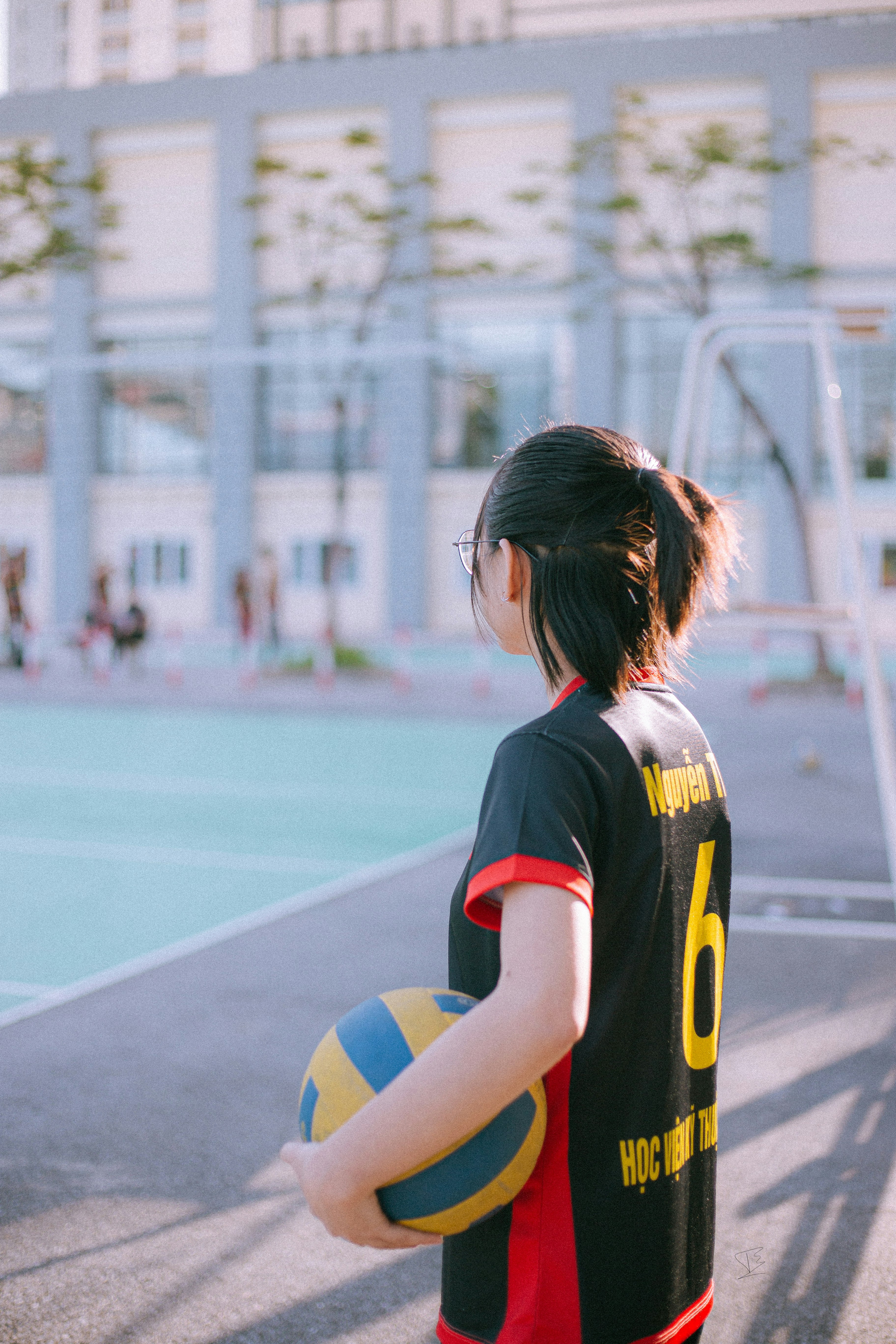 woman in black and yellow jersey shirt standing on track field during daytime