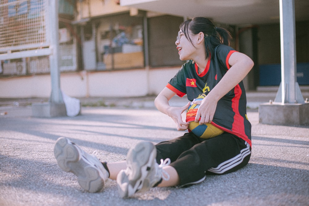 woman in black tank top and black pants sitting on floor with white short coated dog