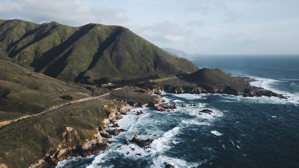 Montaña verde al lado del cuerpo de agua durante el día