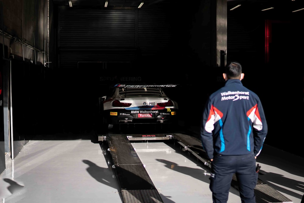 man in blue and red jacket standing beside black car