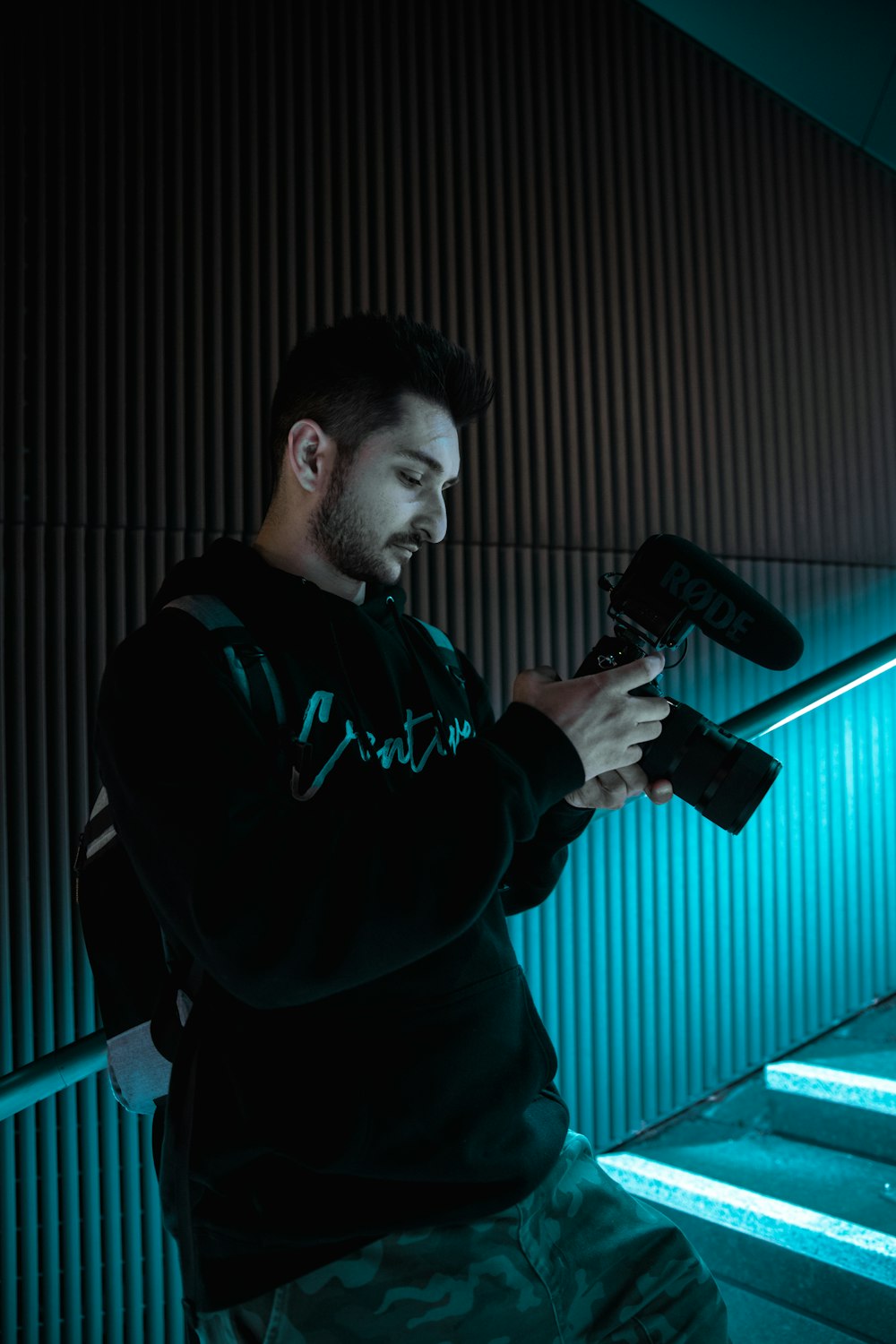 man in black hoodie holding black and red microphone