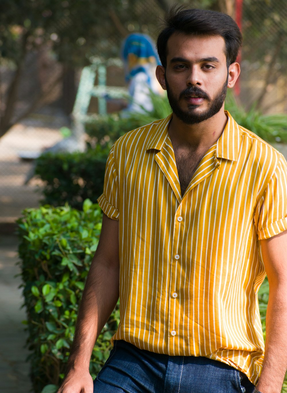 man in yellow and white striped button up shirt standing near green plants during daytime