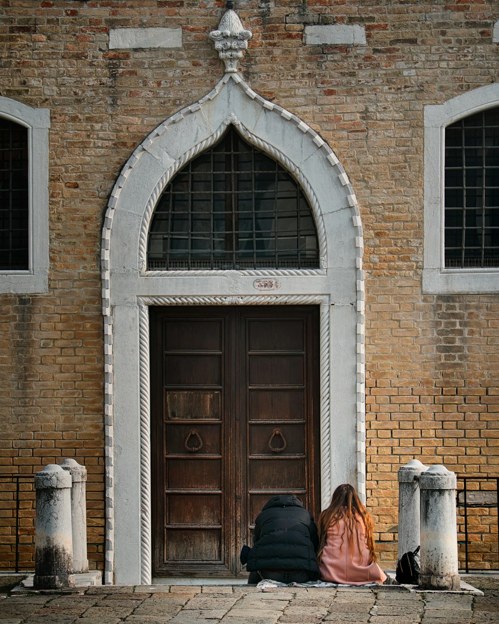 woman in black jacket standing beside brown wooden door