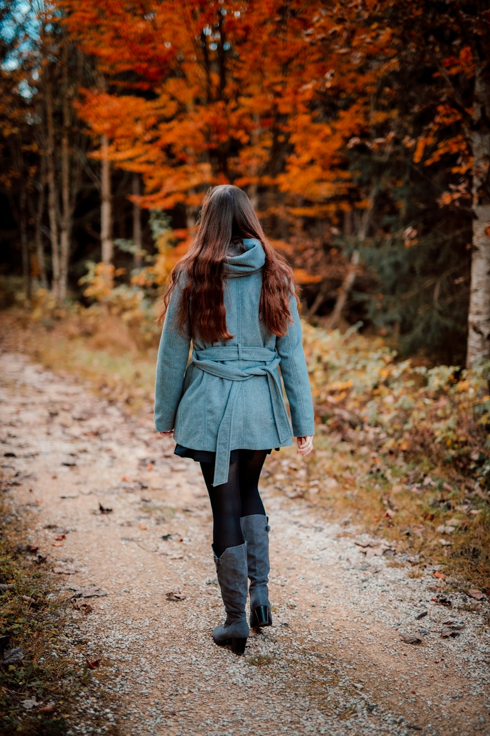 woman in blue coat and black pants walking on road during daytime