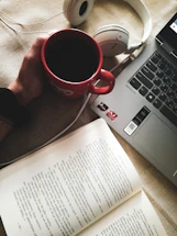A cozy workspace with a laptop open to a video call, surrounded by language learning books and a cup of tea.