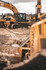 yellow and black excavator on brown soil