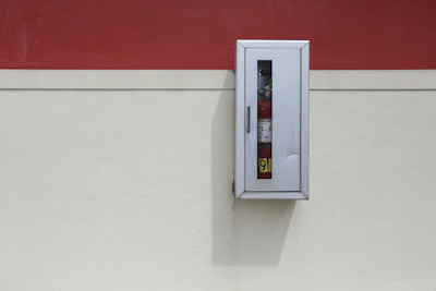 Sleek fire extinguisher mounted on a charcoal-colored wall with safety orange accents.