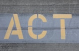 Yellow letters spelling 'ACT' are painted on a textured gray pavement, with visible line separations.