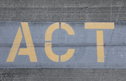 Yellow letters spelling 'ACT' are painted on a textured gray pavement, with visible line separations.