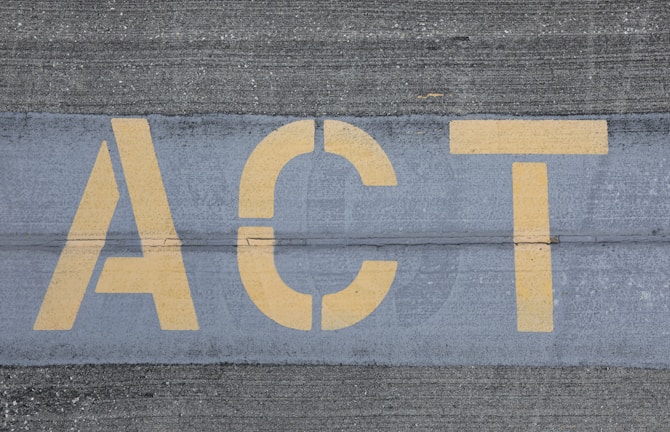 Yellow letters spelling 'ACT' are painted on a textured gray pavement, with visible line separations.