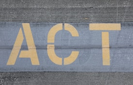 Yellow letters spelling 'ACT' are painted on a textured gray pavement, with visible line separations.