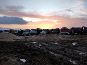 A fleet of trucks lined up ready for heavy cargo transport at sunset.