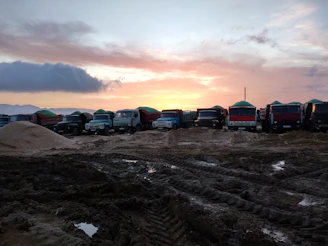 A fleet of trucks lined up outside a distribution center at sunrise.