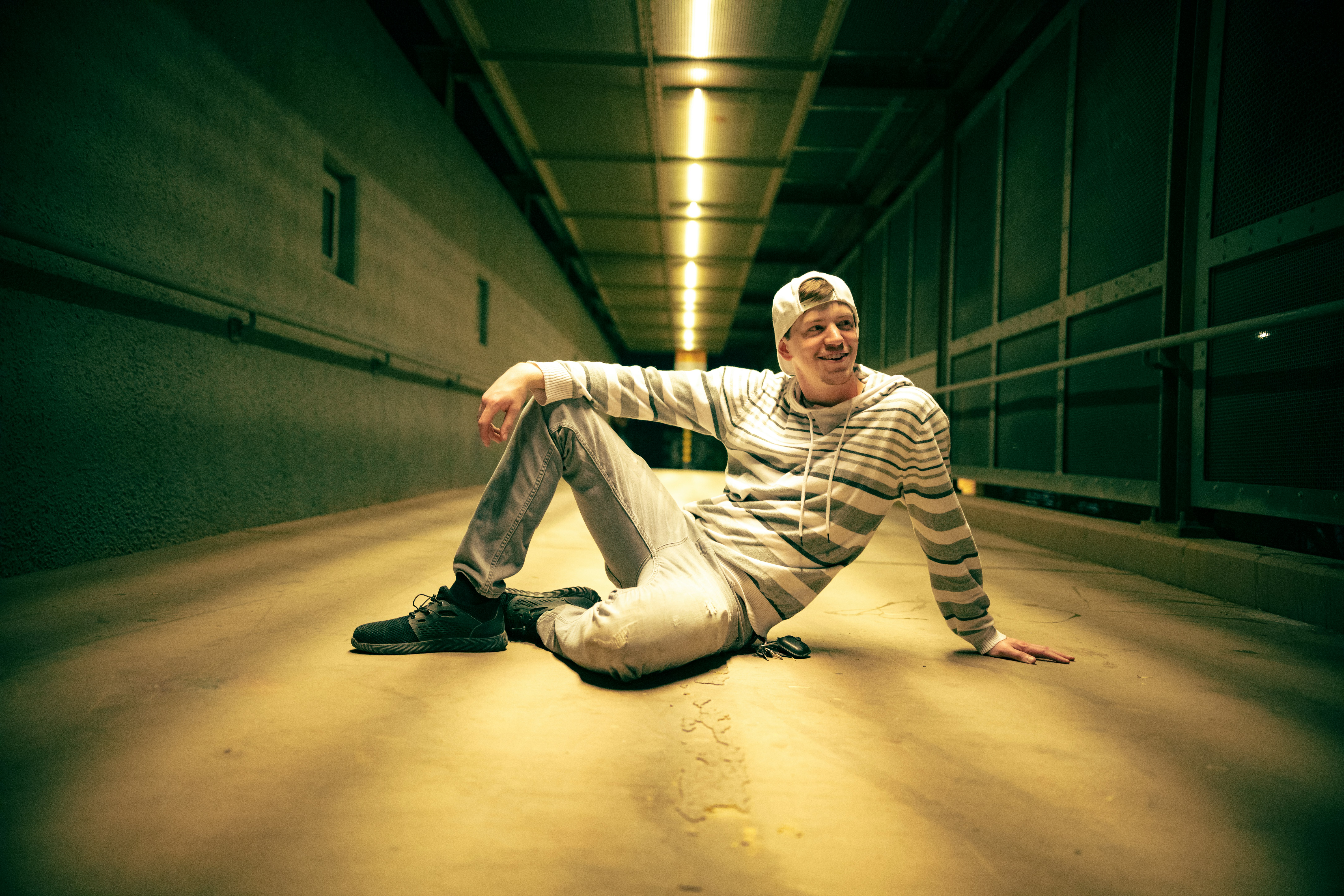 man in white and black striped long sleeve shirt and white pants sitting on brown floor