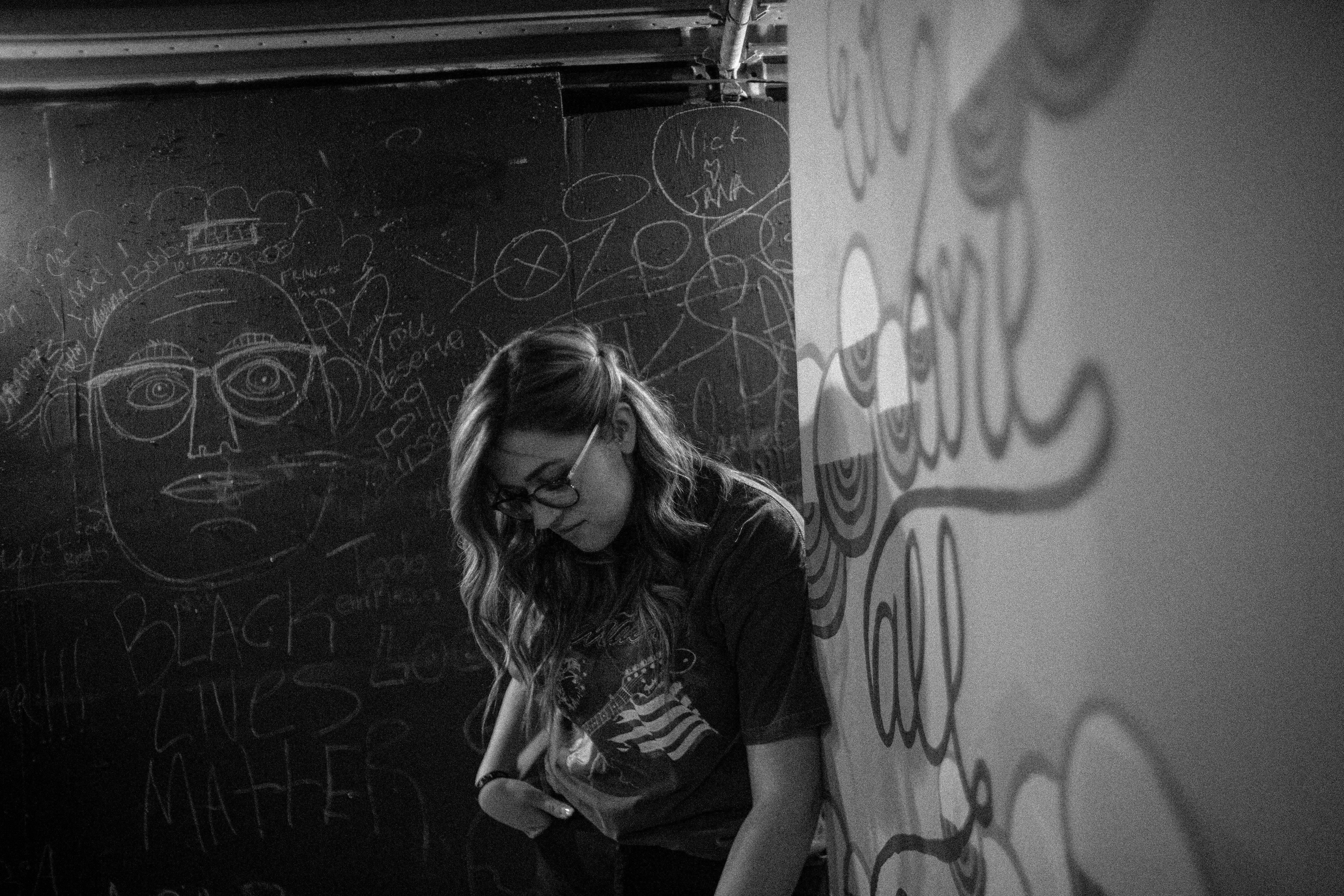 woman in black t-shirt leaning on wall