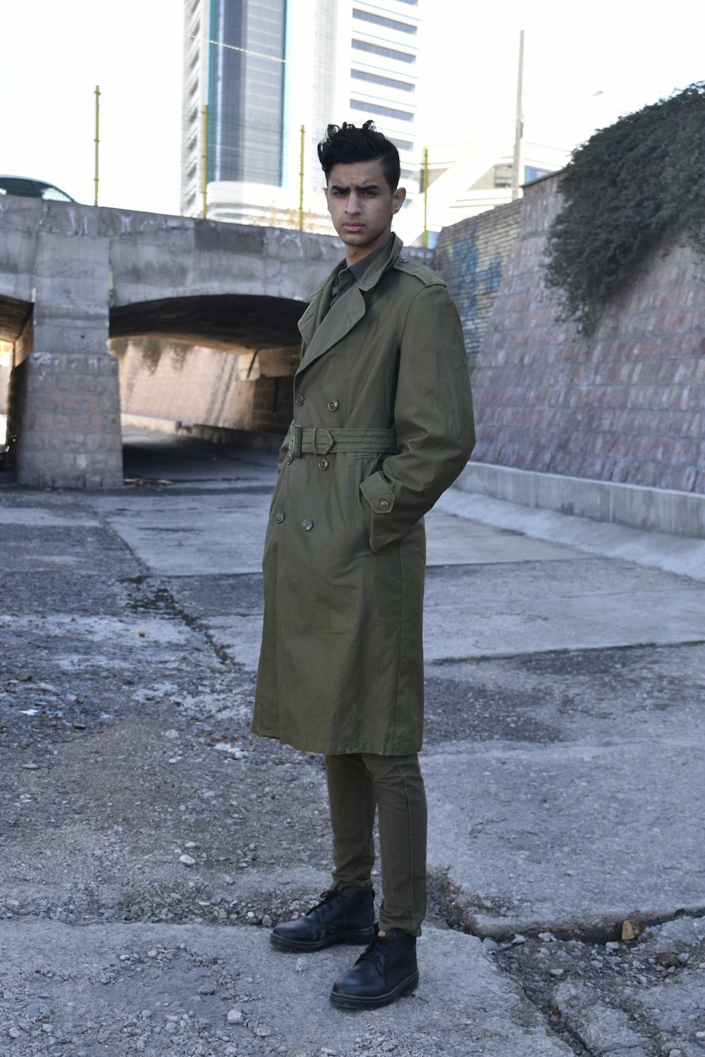a man in a trench coat standing on a street